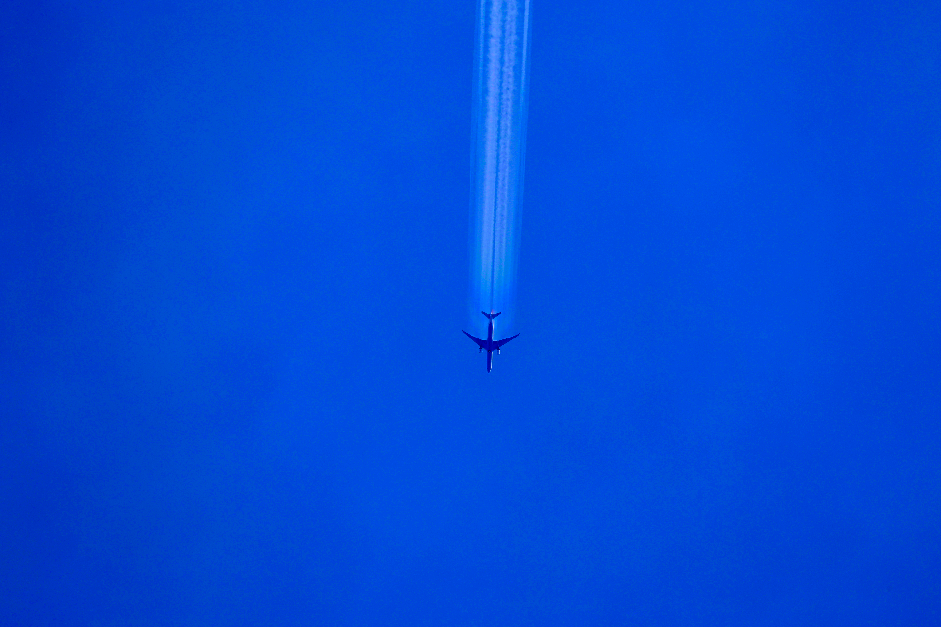 Contrail — aircraft against deep blue sky